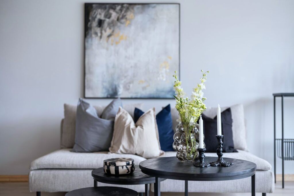 Graues Sofa mit Dekokissen und schwarzen Beistelltischen