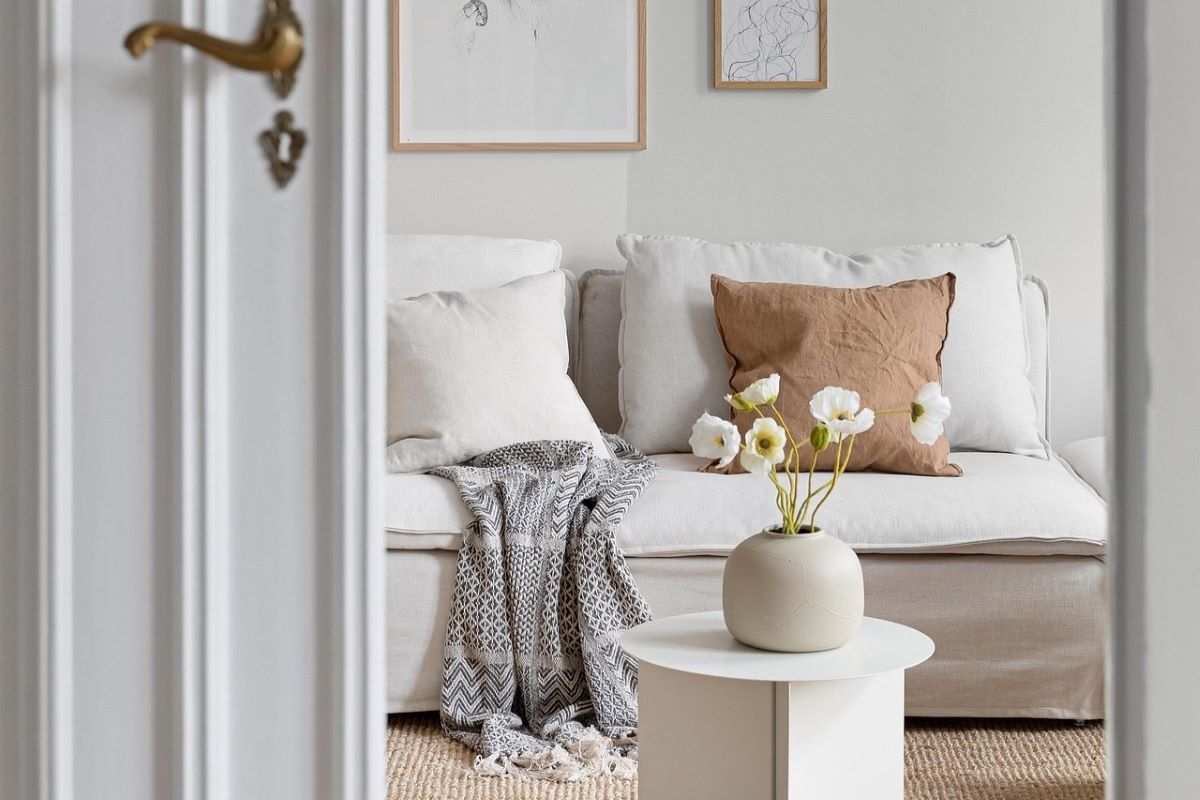 Blick in ein Wohnzimmer mit weißem Sofa und dezenter Deko in Naturtönen